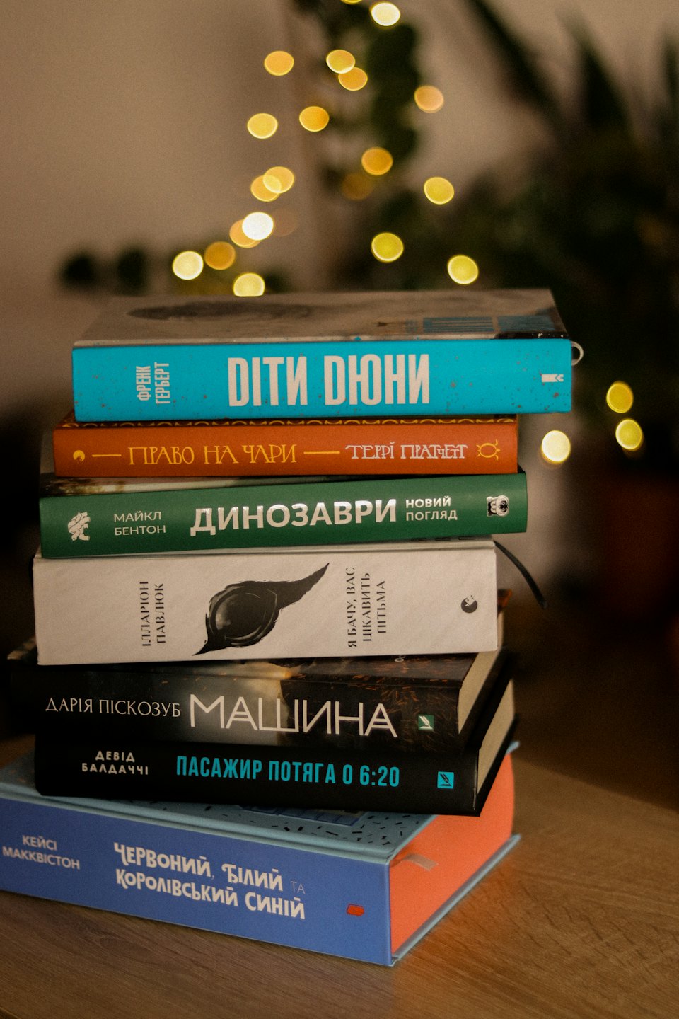 Sei libri con dorsi vari sono impilati su una superficie di legno.
