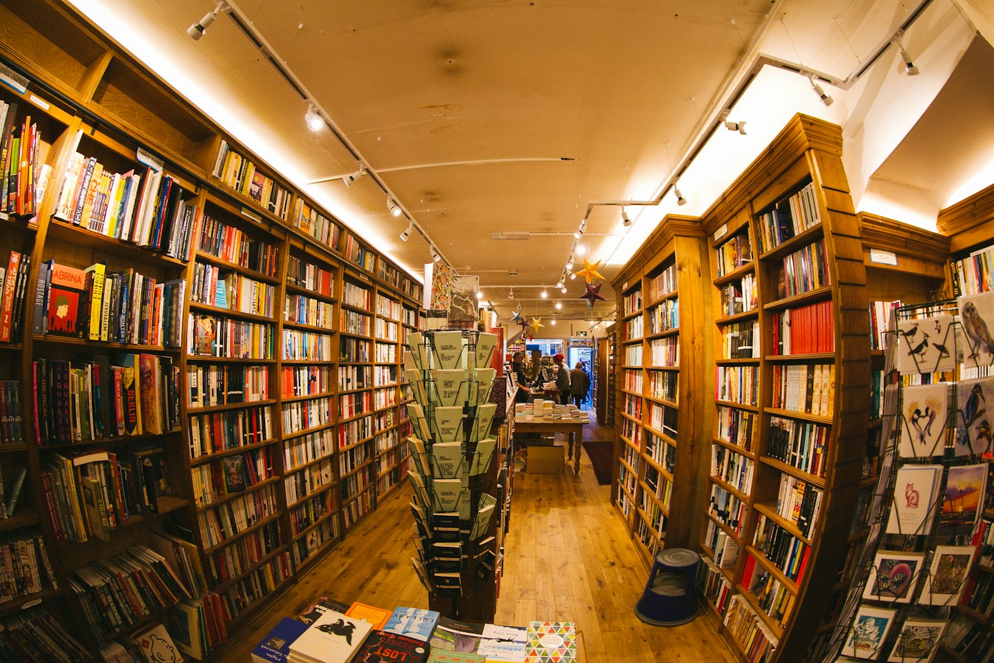 Clienti che sfogliano libri in uno stretto corridoio di libreria.