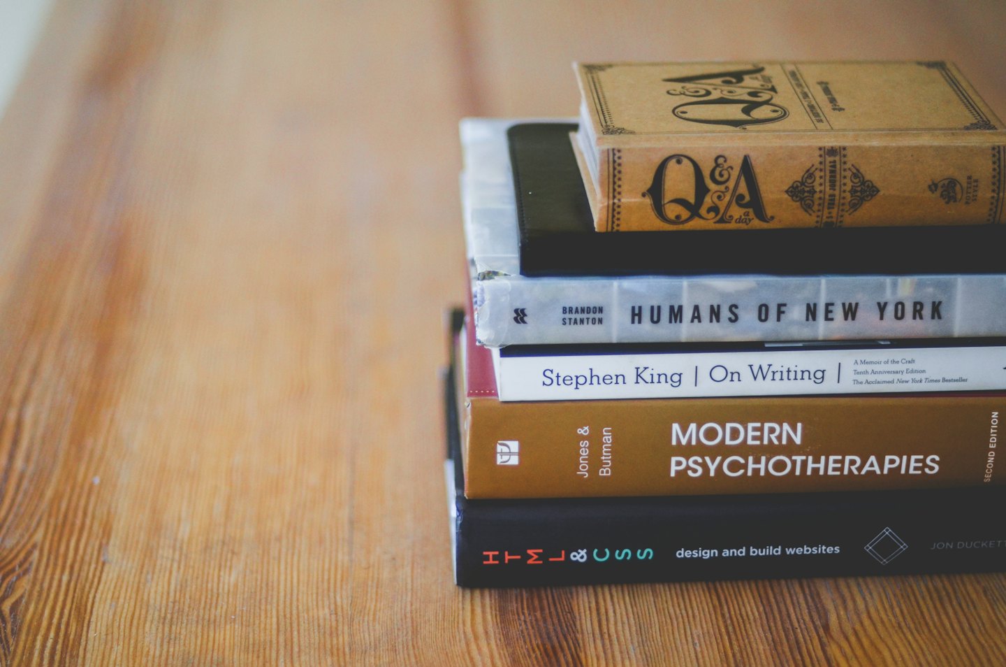 Cinque libri impilati su un tavolo di legno.